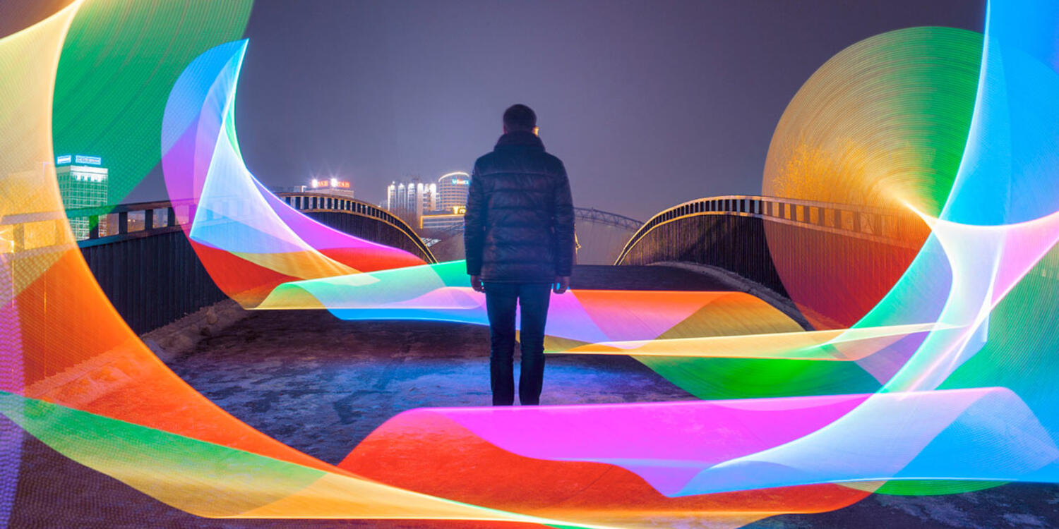 An artistic representation of rainbow lights over a black and white photo.