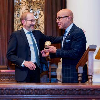 2025 MLK lecturer Darren Walker being handed an award by Alan Garber, president of Harvard University.