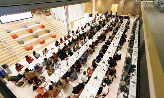 An aerial shot of approx. 150 attendees seated at long tables at the Across This Table interfaith dinner.