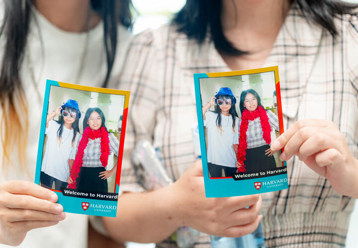 Attendees at Community and Campus Life's Welcome to Harvard event hold up their photo booth favors.