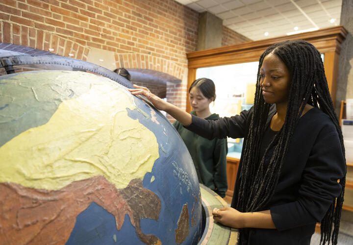 A Harvard College student using a very large tactile globe.