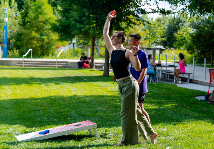 A Harvard community member playing cornhole outdoors.