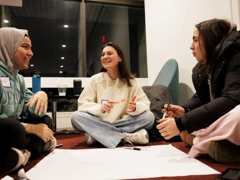 Three students sitting on the ground and working together during an event. 
