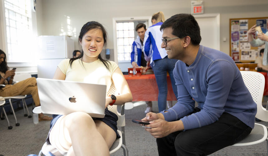 Two Harvard community members in conversation looking at a laptop