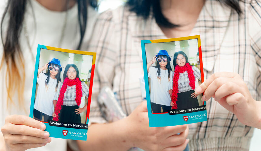 Attendees at Community and Campus Life's Welcome to Harvard event hold up their photo booth favors.