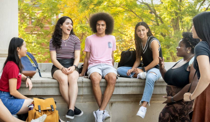 Harvard students engaged in conversation outdoors on Harvard campus.