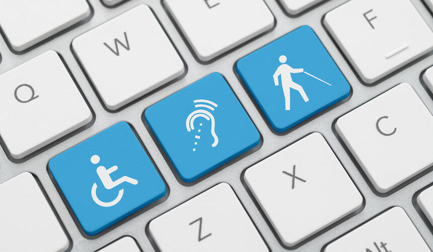 A computer keyboard with keys showing symbols indicating a wheelchair, hard of hearing, and low vision/blind. 