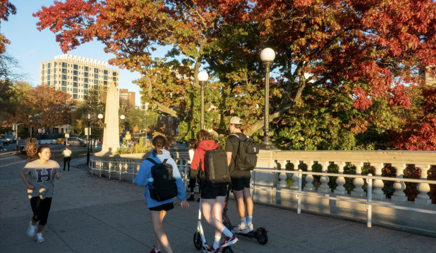 Three individuals walking together outdoors with colorful fall foliage in the background.