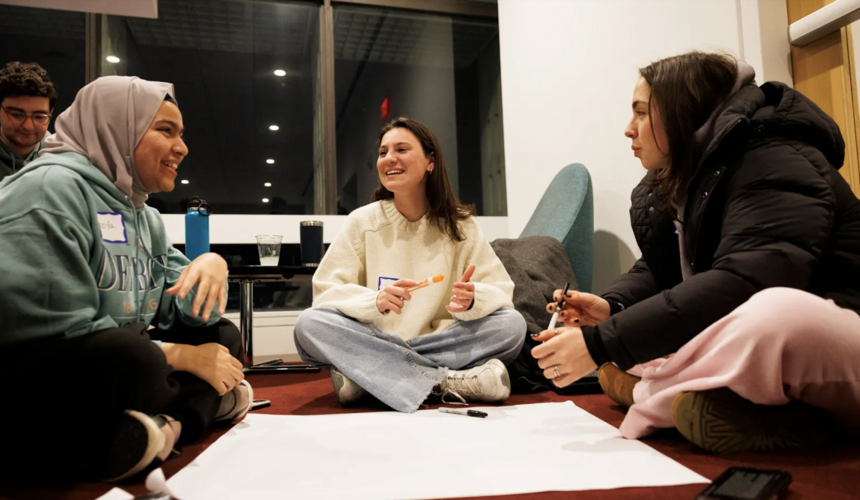 Three students sitting on the ground and working together during an event. 