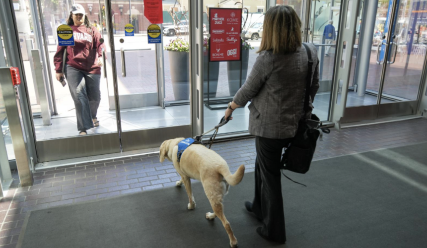 Woman walking with an assistance dog out of the Smith Campus Center. 