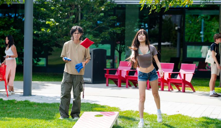 A Harvard community member plays cornhole.